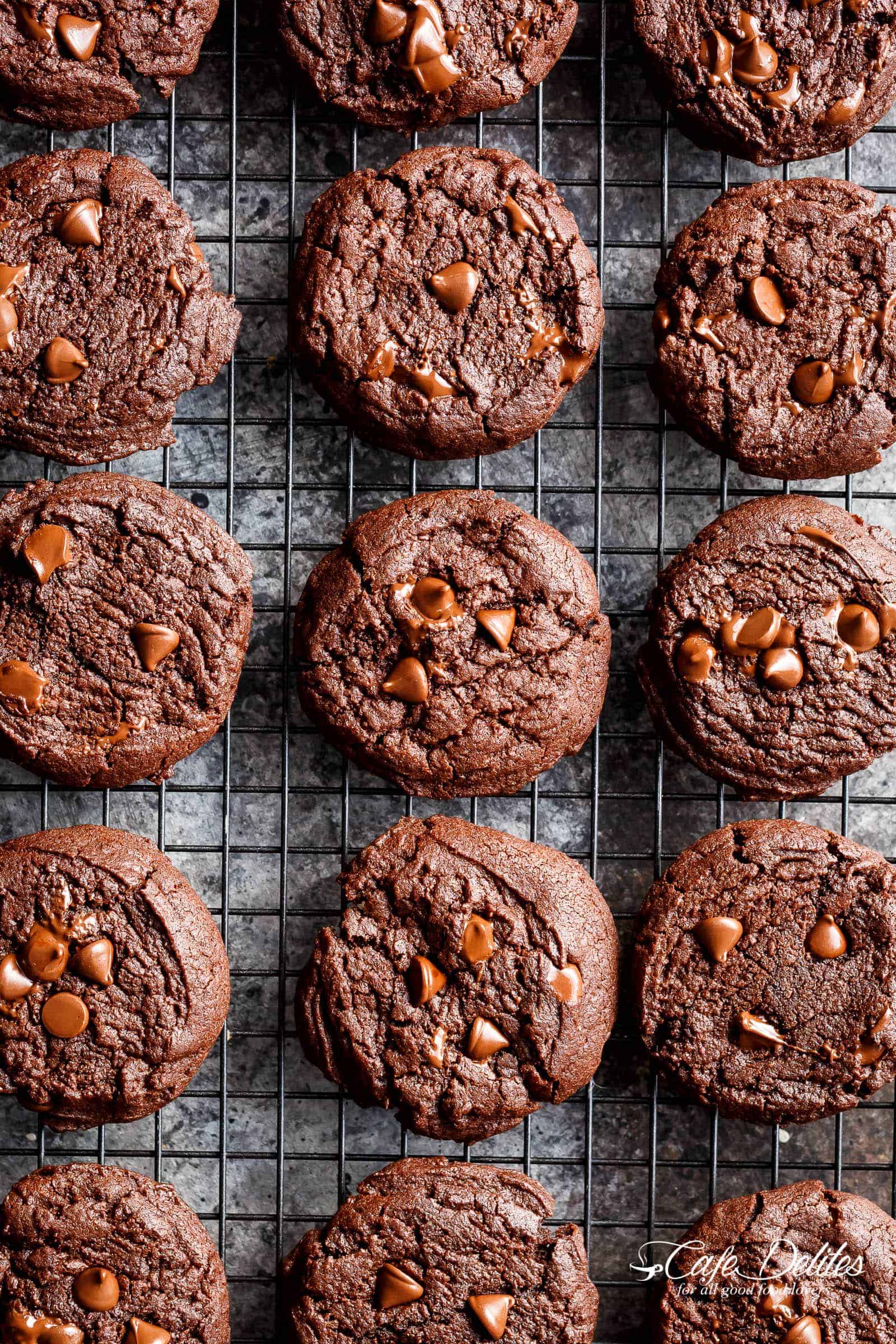 Bird's eye view of finished cookies on a cooling rack with shiny chocolate chips visible across the surface of each one. 