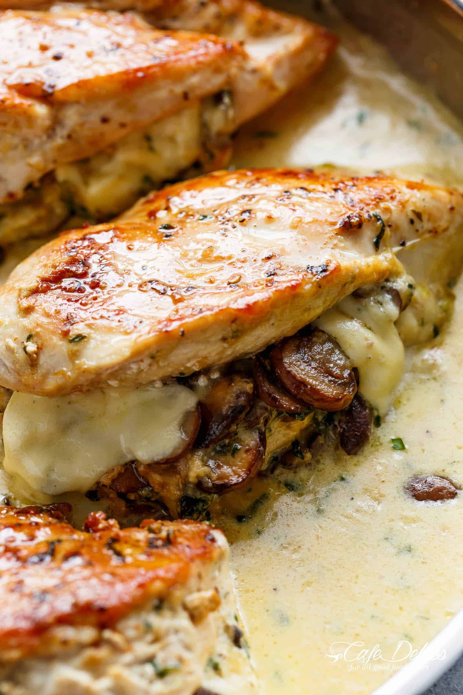 A close up image of cheesy mushrooms stuffed in a seared cooked chicken breast in a cream sauce