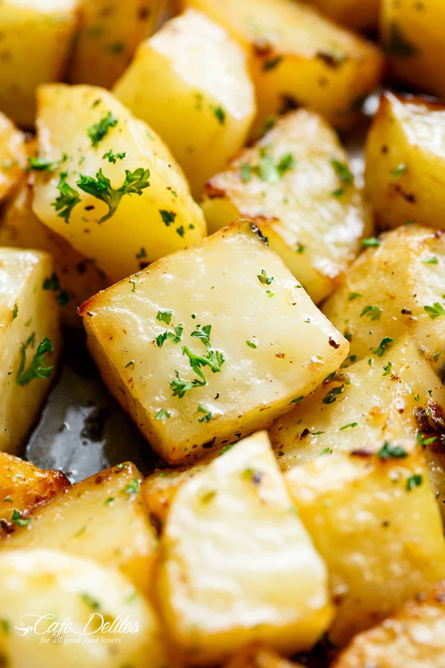 Close up on crispy roasted potatoes garnished with chopped parsley.