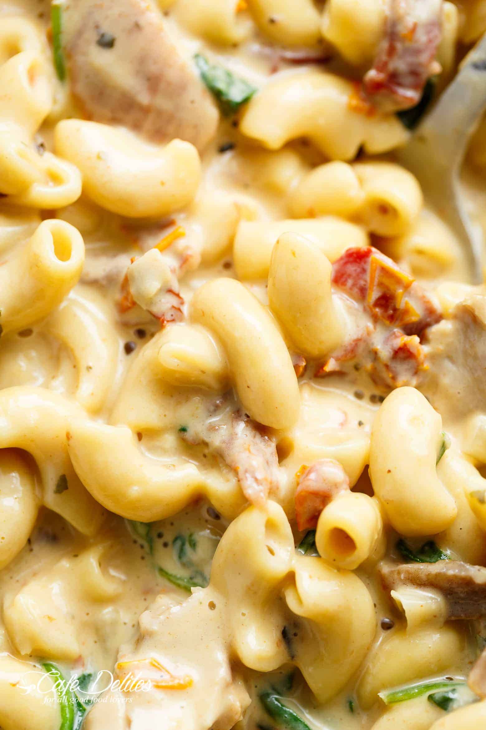 A close up image of Tuscan Mac and cheese being scooped up with a serving spoon.