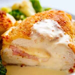 Side view of Crispy crumbed chicken breasts filled with Dijon mustard, Swiss cheese and ham, baked with vegetables and served with an incredible Dijon Cream Sauce