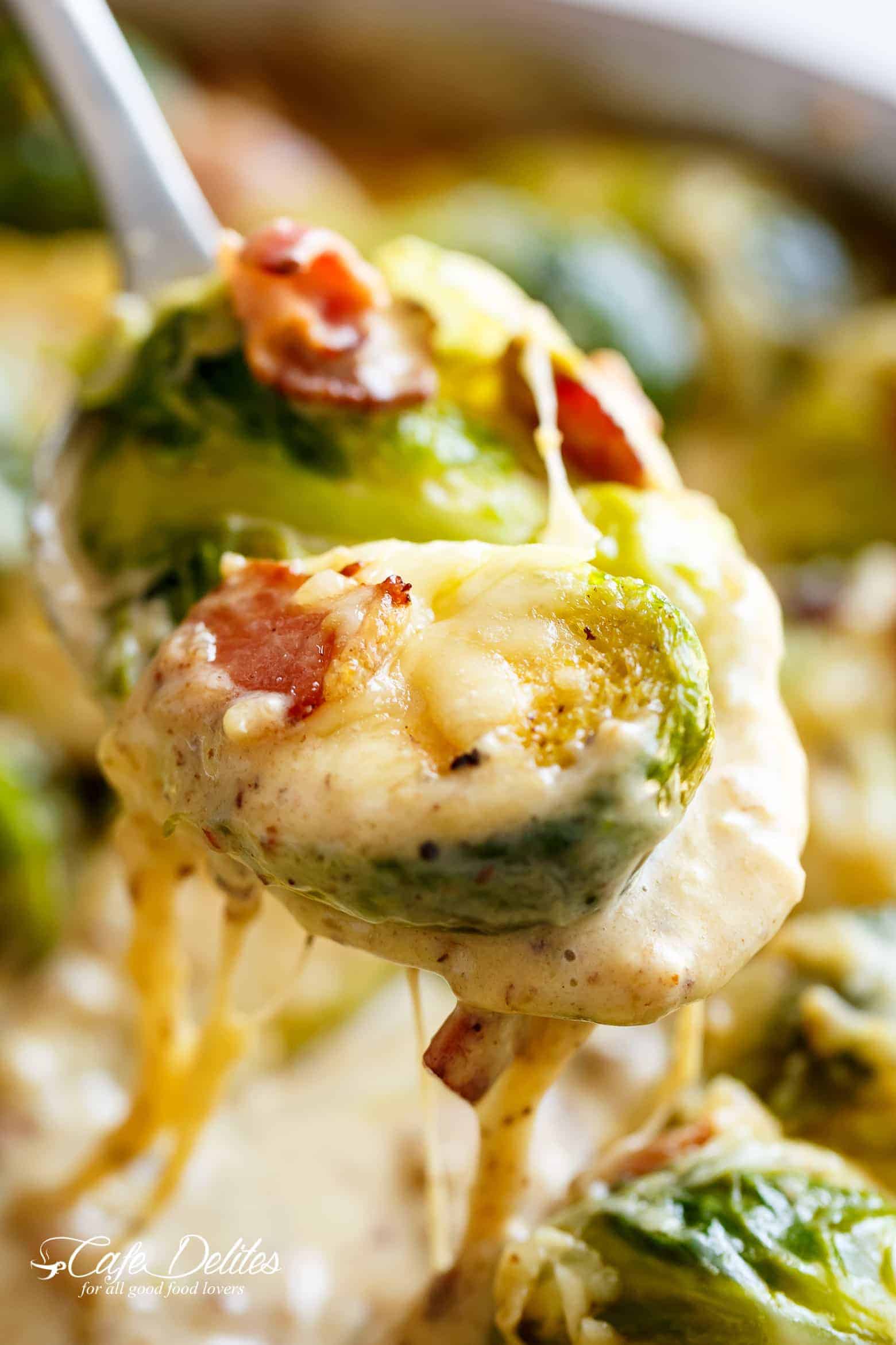 Brussel Sprouts with Bacon in a cheese sauce scooped up with a metal spoon ready to serve.