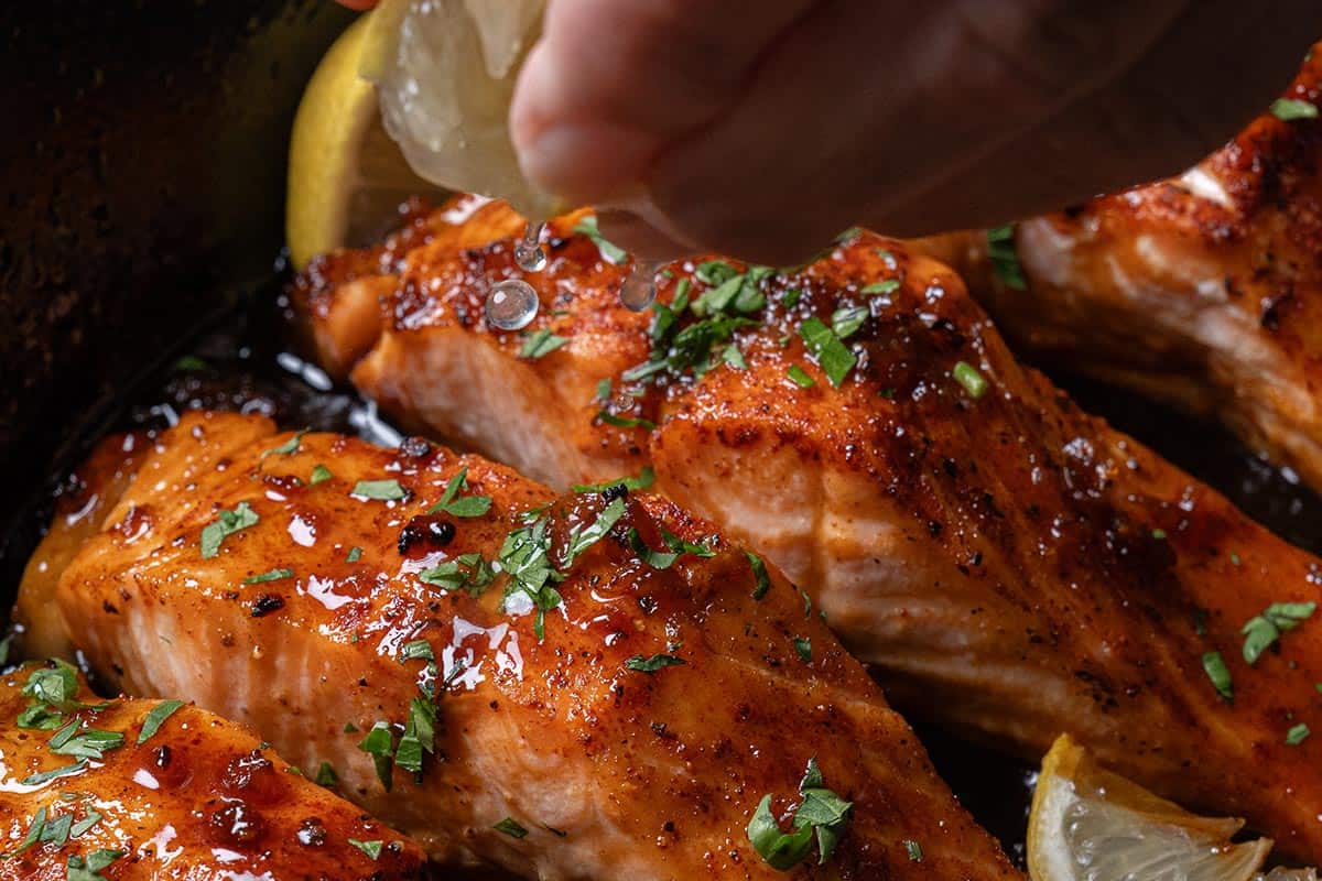 Close-up image of the salmon, ready to be served, with fresh parsley sprinkled on top and drizzled with a squeeze of lemon juice.