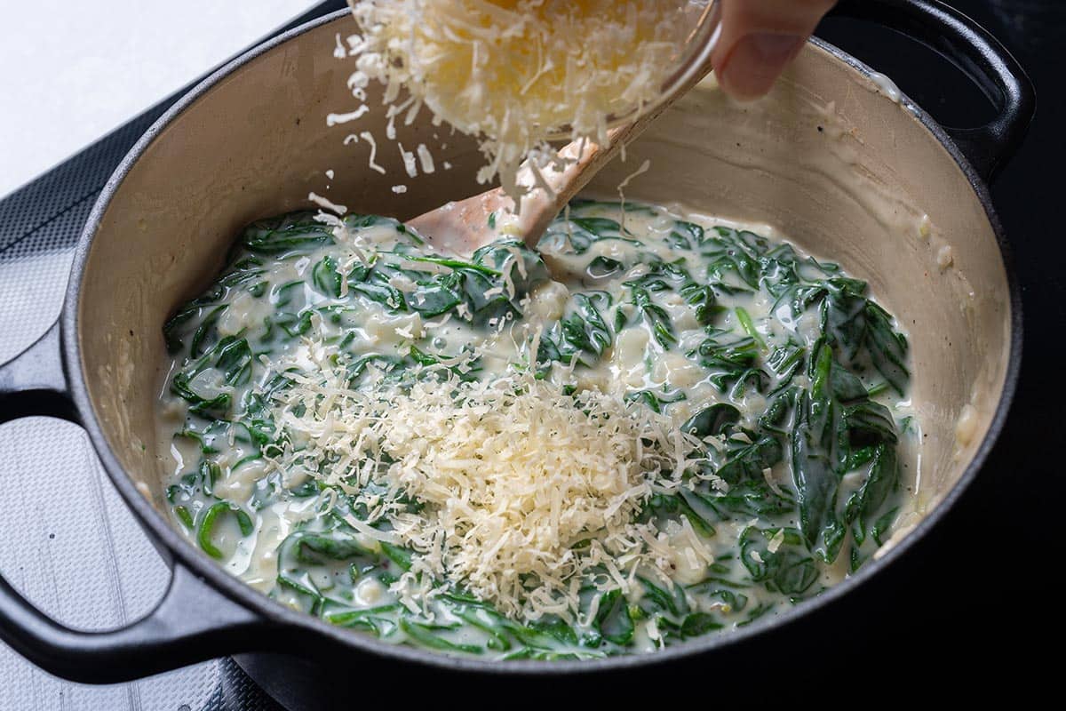 easy creamy spinach in a pot having cheese sprinkles over it