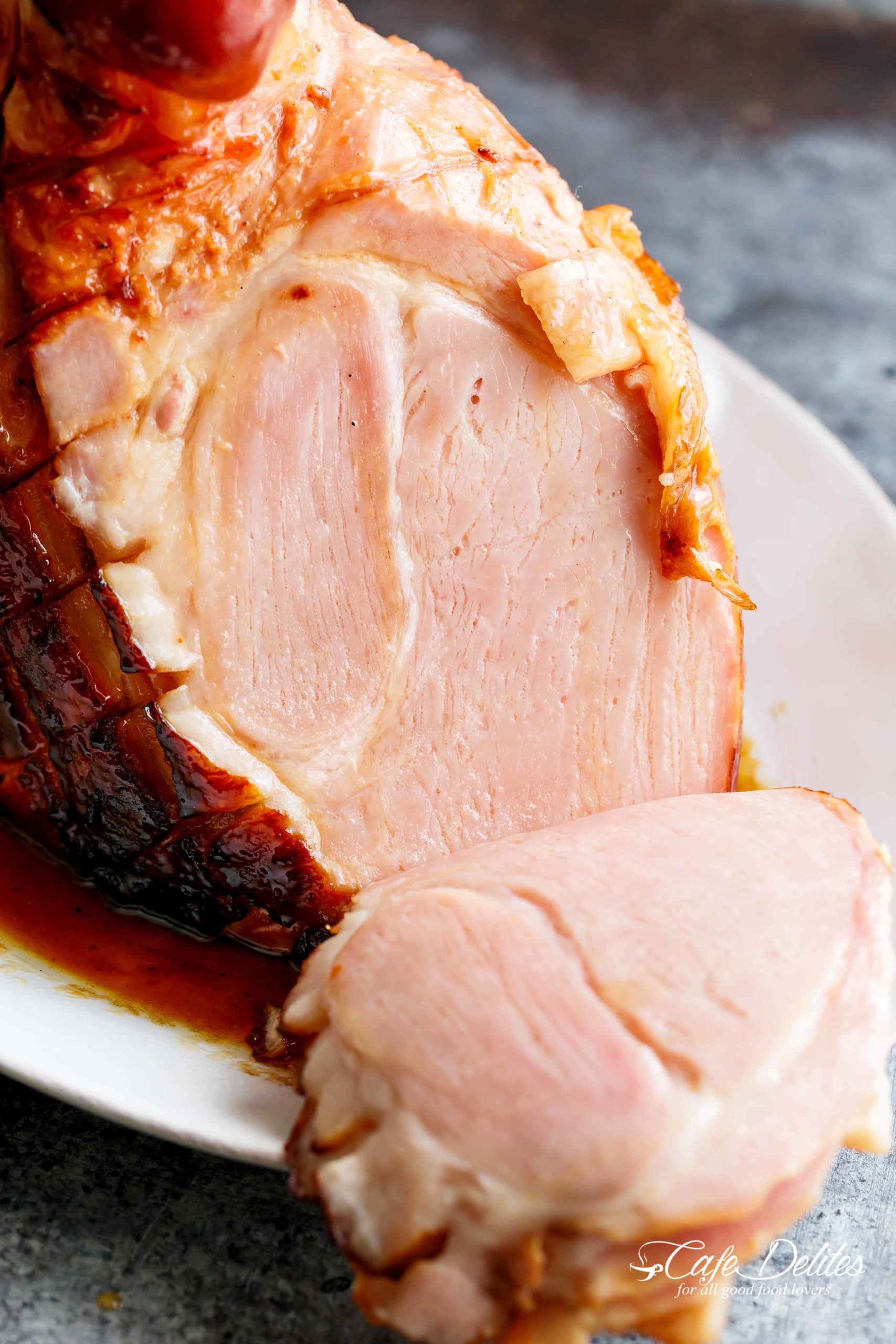 The finished glazed ham with a large slice cut and falling from the rest of the meat. 