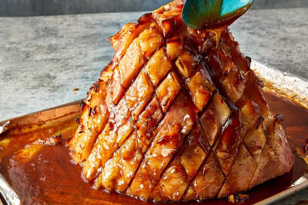 a side view of a cooked ham with glaze being poured on top of it - 16