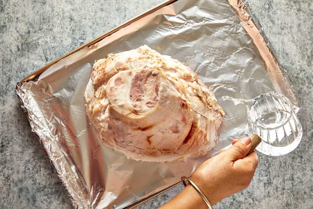 a top down view of a leg ham sitting on aluminum foil, the leg is sitting cut side down looking like a mountain from top down and exposing the fatty layer - 11