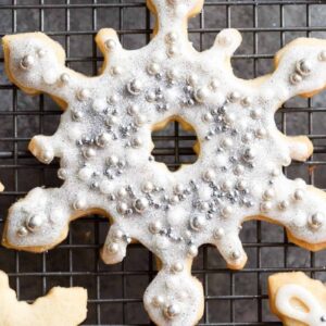 christmas star cookie with silver speckle topping resting on a wire rack