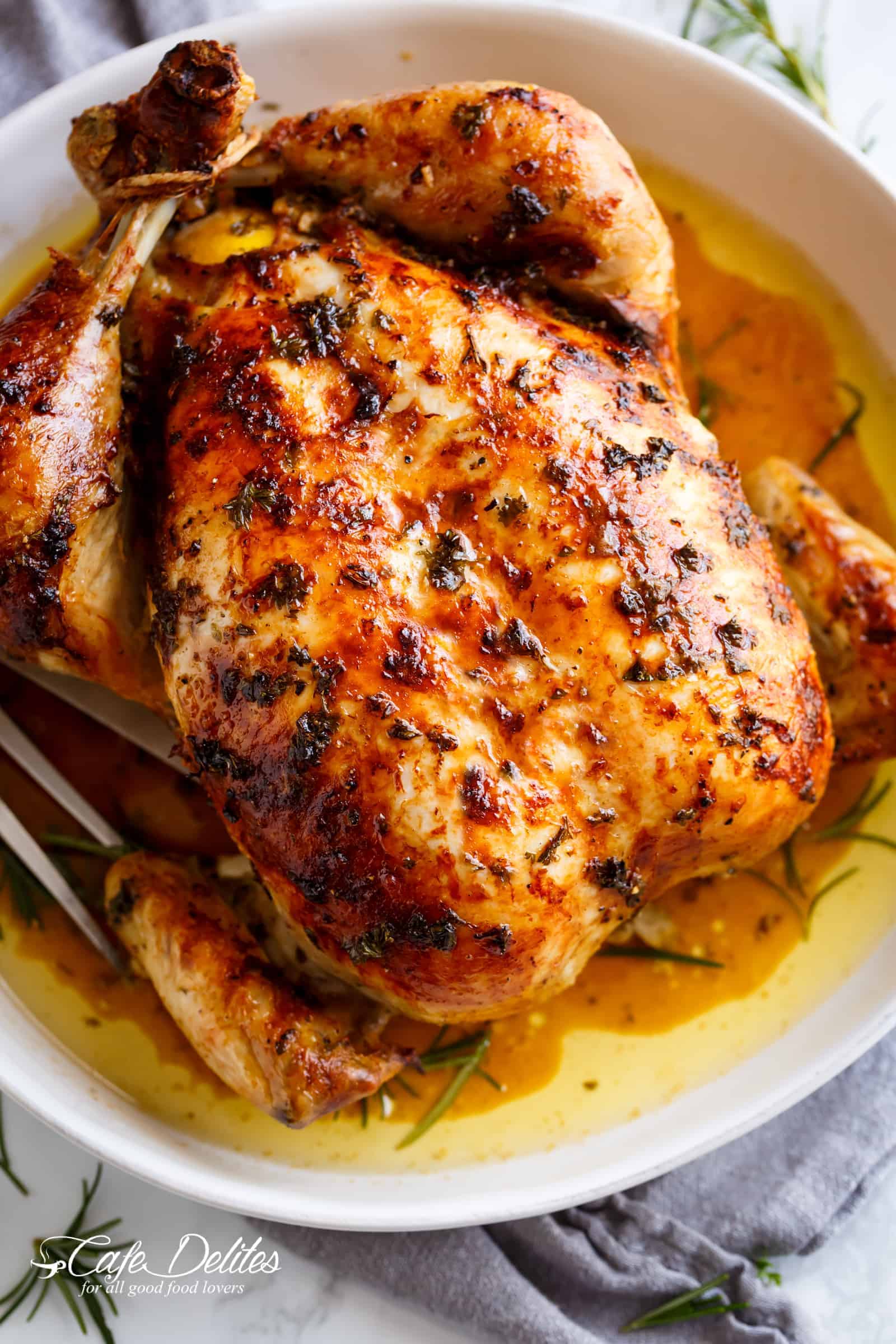  Garlic Herb Butter Roast Chicken beats rotisserie chicken! Served on a white plate with drippings and fresh herbs | cafedelites.com