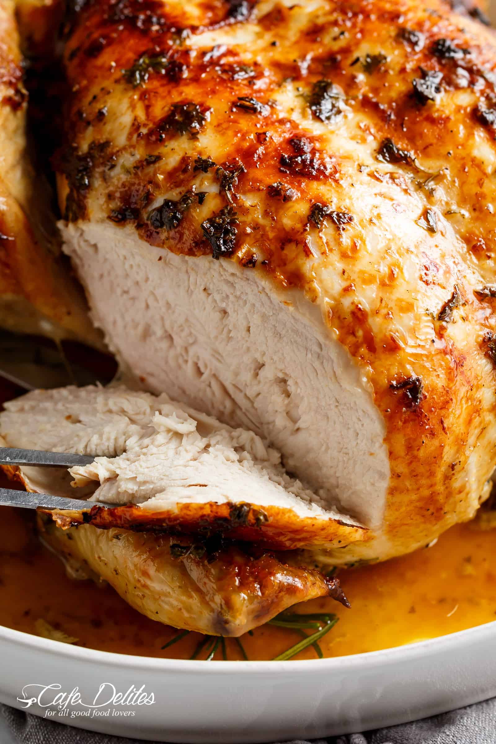 Close up of whole cooked chicken sliced through the breast to reveal the moist white flesh.