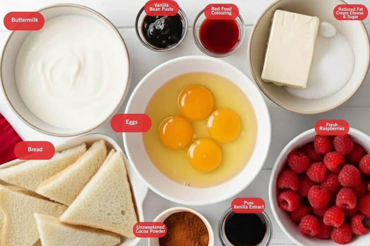 Flat lay photo of ingredient shot of buttermilk, vanilla bean paste, red food coloring, reduced fat cream cheese and sugar, fresh raspberries, pure vanilla extract, unsweetened cocoa powder, bread, eggs