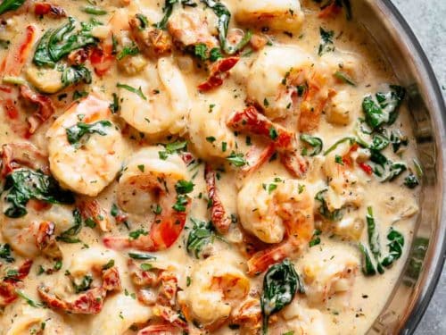 Creamy Garlic Butter Tuscan Shrimp coated in a light and creamy sauce filled with garlic, sun dried tomatoes and spinach in a pan