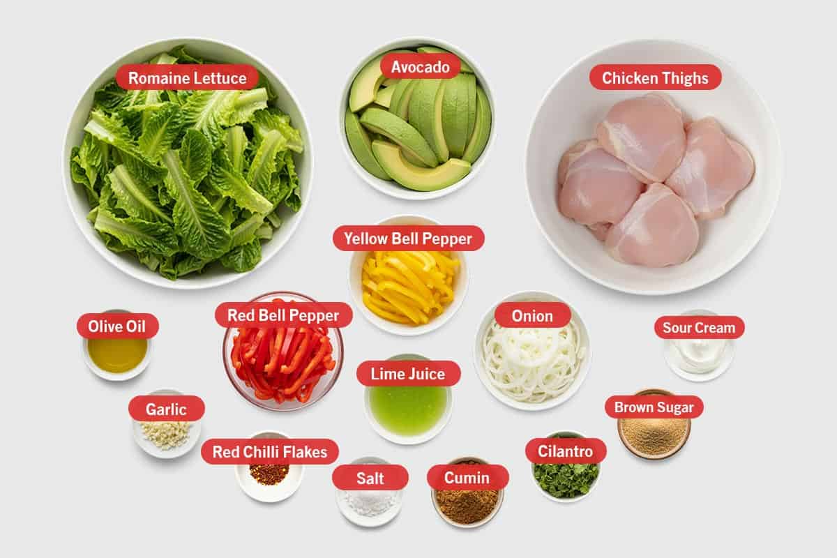 Top shot of ingredients: Romaine lettuce, avocado, chicken thighs, yellow bell pepper, red bell pepper, lime juice, onion, olive oil, garlic, red chilli flakes, salt, cumin, cilantro, brown sugar, and sour cream.