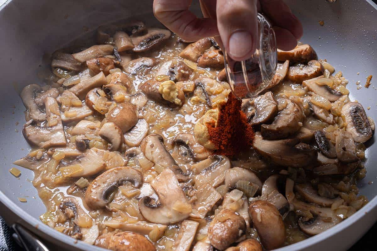 Vegetables being cooked in the same pan where steak chunks, which have now been set aside, were cooking.