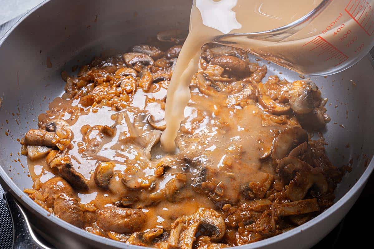 beef broth and worcestershire sauce being added to the pan where vegetables where cooking.