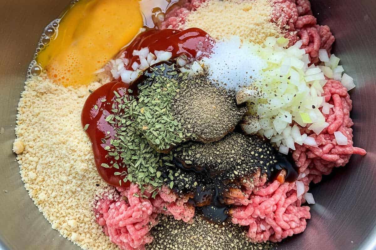 Beef, breadcrumbs, onion, seasoning, ketchup, Worcestershire, egg, salt, and pepper in a bowl.