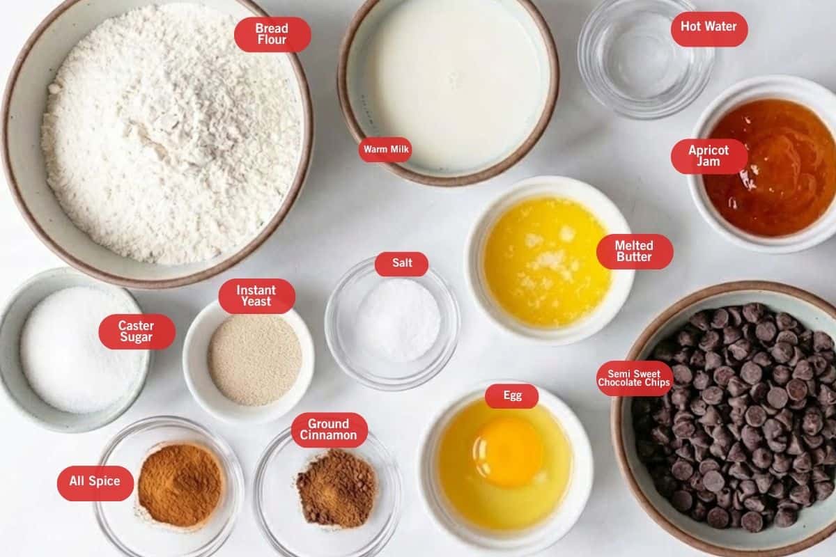 Flat lay photo of ingredient shot of bread flour, warm milk, hot water, apricot jam, melted butter, semi sweet chocolate chips, egg, ground cinnamon, salt, instant yeast, all spice. caster sugar