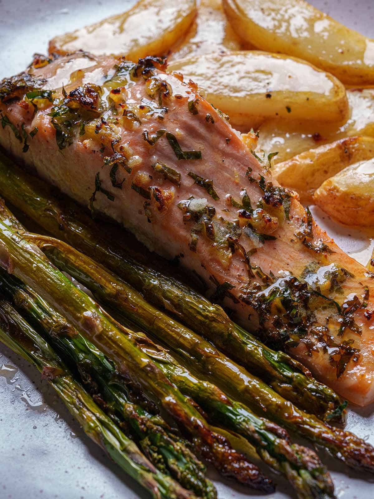 Close-up image of a tender and juicy salmon darne, complemented by asparagus and baked potatoes.