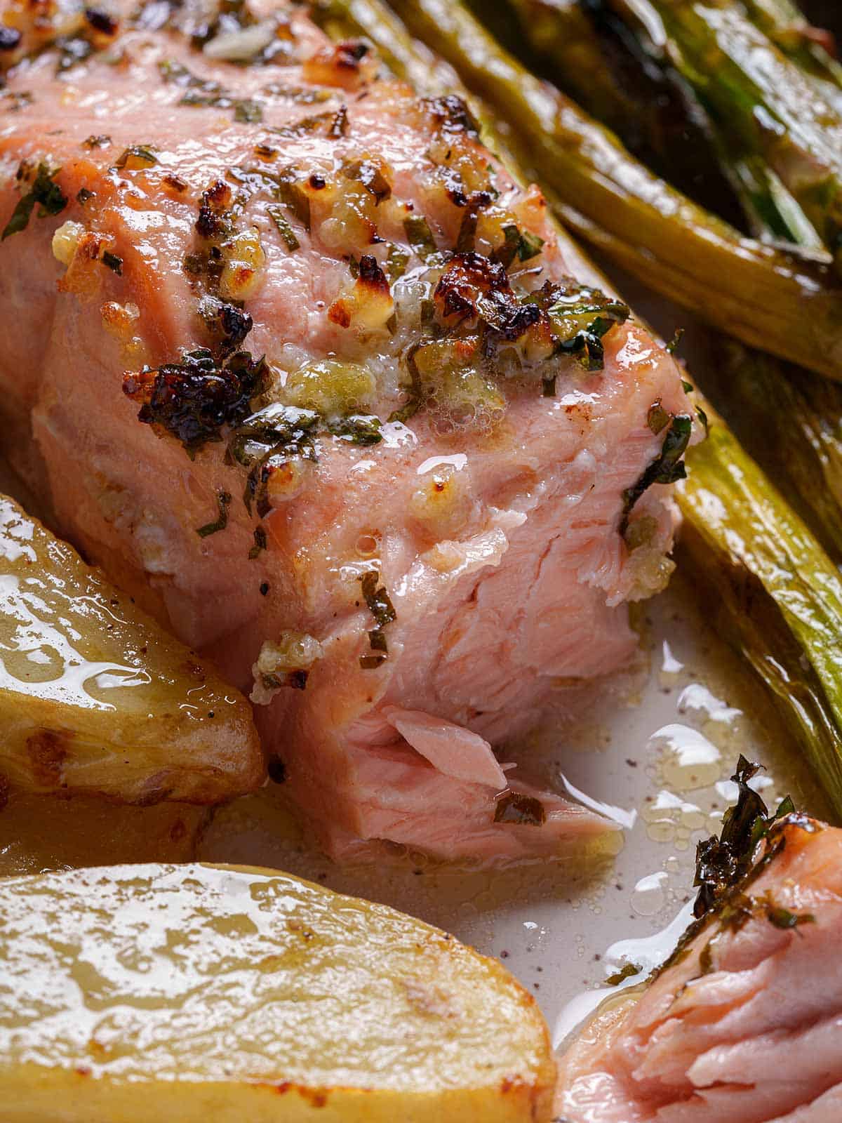 Close-up of a perfectly cooked salmon fillet, gently pulled apart by a golden fork, revealing its flaky and tender texture.