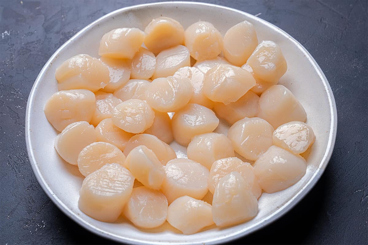 An image of the scallops, laid out in a white bowl, is ready to be used in our recipe.