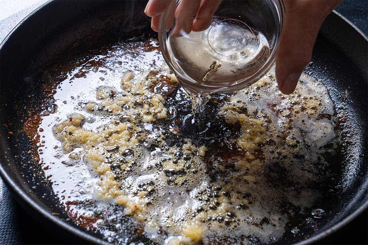 Image of wine being added to the frying pan.