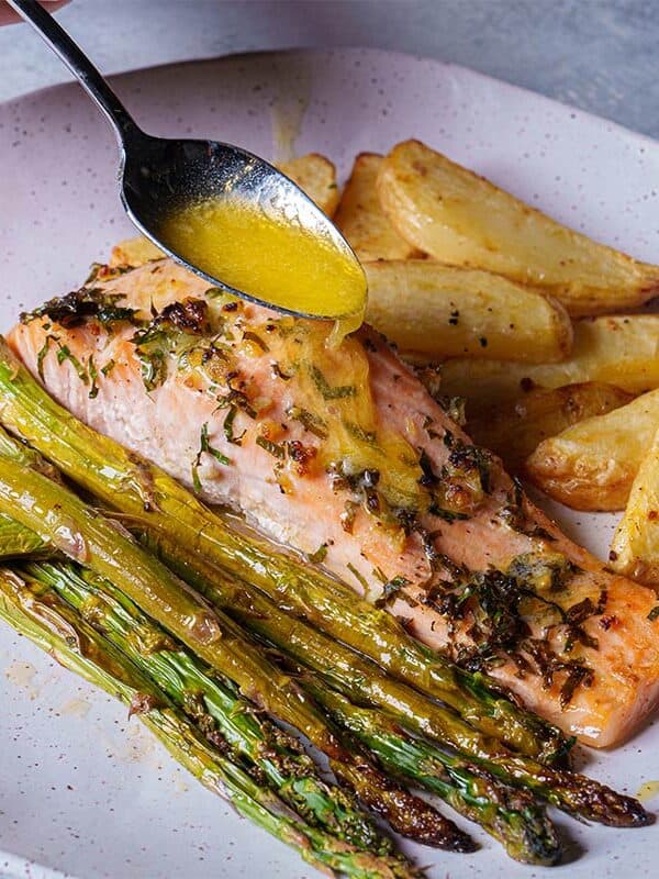 Close-up of a perfectly cooked salmon fillet, gently pulled apart by a golden fork, revealing its flaky and tender texture.