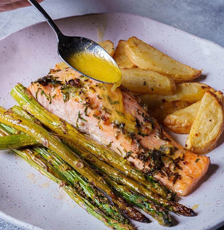 Close-up of a perfectly cooked salmon fillet, gently pulled apart by a golden fork, revealing its flaky and tender texture.