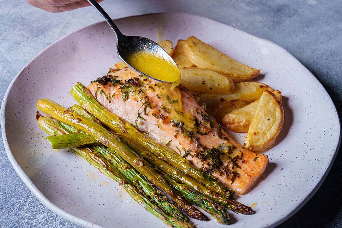 Perfectly cooked salmon with charred edges, sprinkled with sauce, ready to be served.