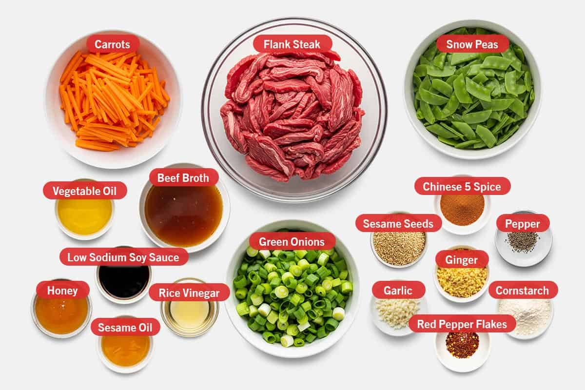 Top shot of ingredients: Carrots, flank steak, snow peas, vegetable oil, beef broth, low sodium soy sauce, honey, sesame oil, rice vinegar, green onions, Chinese 5 spice, sesame seeds, ginger, pepper, garlic, red pepper flakes, and cornstarch.