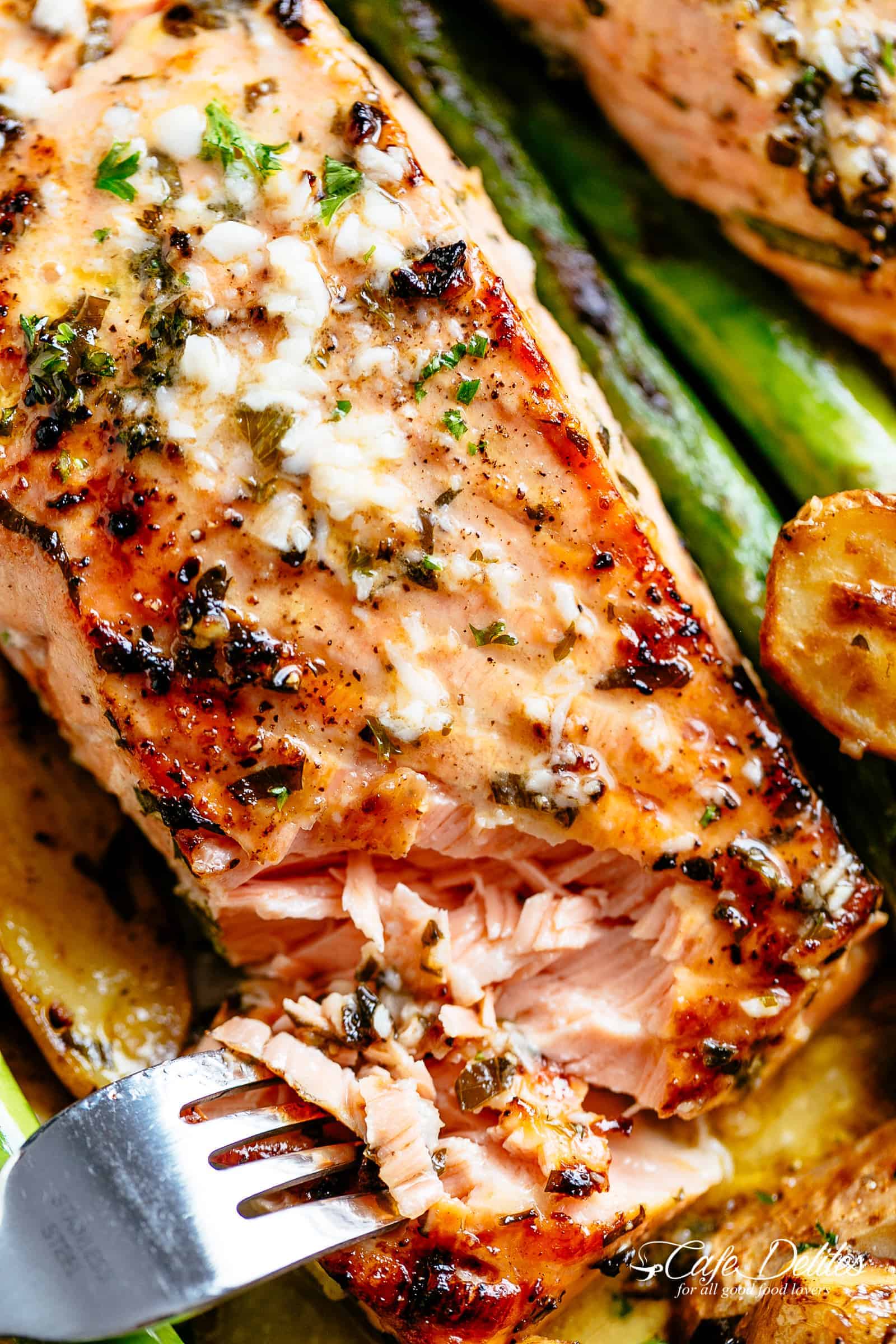 A closeup of a fork pulling open a tender salmon fillet. 