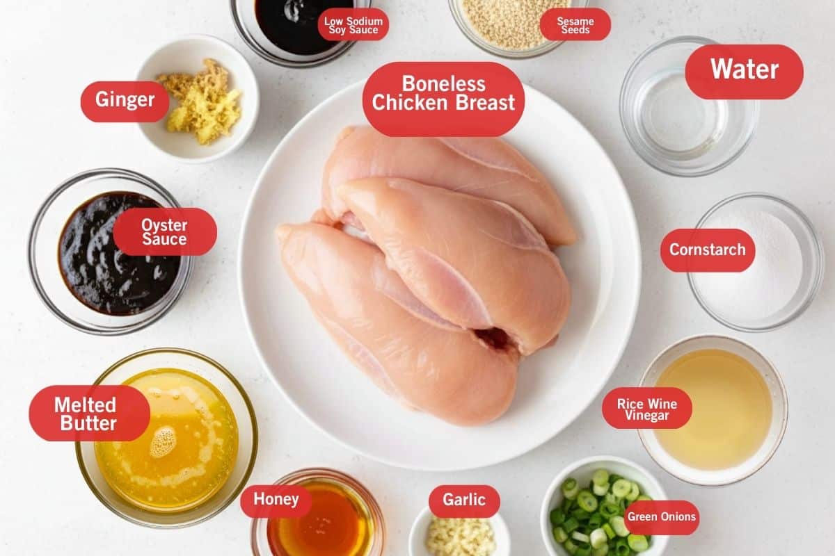 Flat lay of ingredient shot ginger, low sodium soy sauce, sesame seeds, water, cornstarch, rice wine vinegar, green onions, garlic, honey, melted butter, oyster sauce, boneless chicken breast.