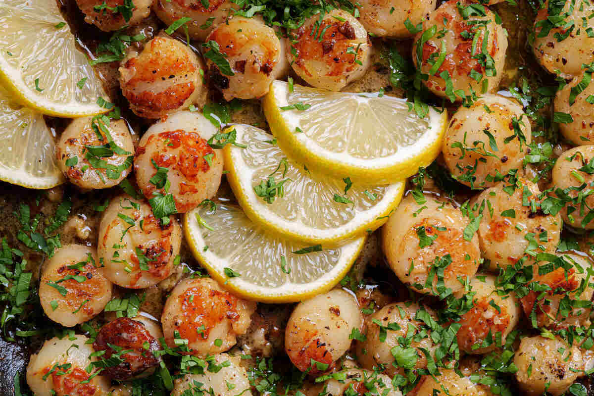 Image of scallops garnished with fresh, chopped parsley.