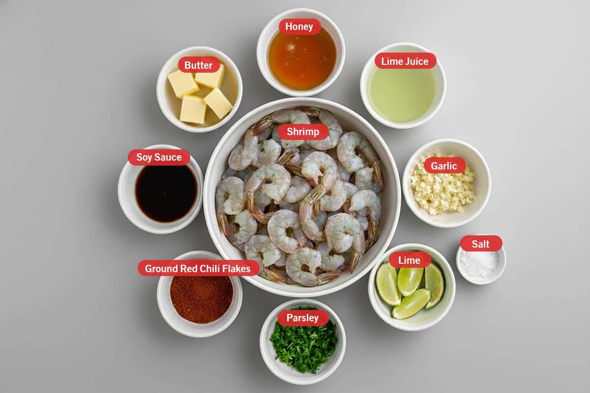 Top shot of ingredients: honey, lime juice, garlic, lime, salt, parsley, ground chilli flakes, soy sauce, butter, and shrimp. - 2