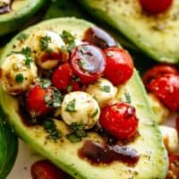 Basil Pesto Caprese Stuffed Avocado drizzled with balsamic glaze make an incredible light lunch or snack! Take creamy avocados to a different level! Sweet and juicy grape/cherry tomatoes with fresh mozzarella balls are tossed through basil pesto and spooned into avocado halves! | cafedelites.com