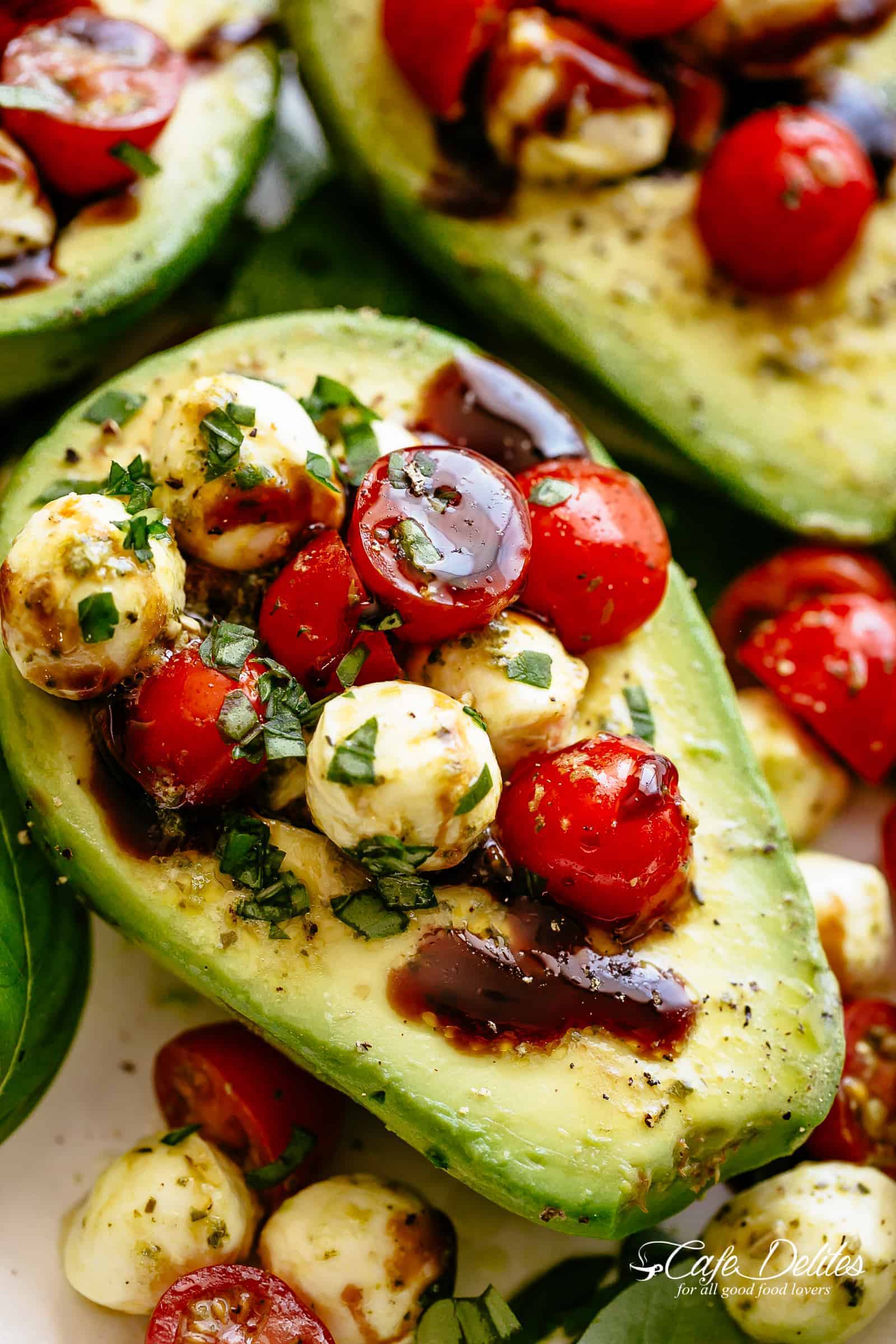 Basilikapesto Caprese fylld avokado som droppas med balsamicoglasyr är en otrolig lätt lunch eller mellanmål! Ta krämiga avokados till en annan nivå! Söta och saftiga druv-/körsbärstomater med färska mozzarellabollar kastas genom basilikapesto och sköljs ner i avokadohalvor! | cafedelites.com