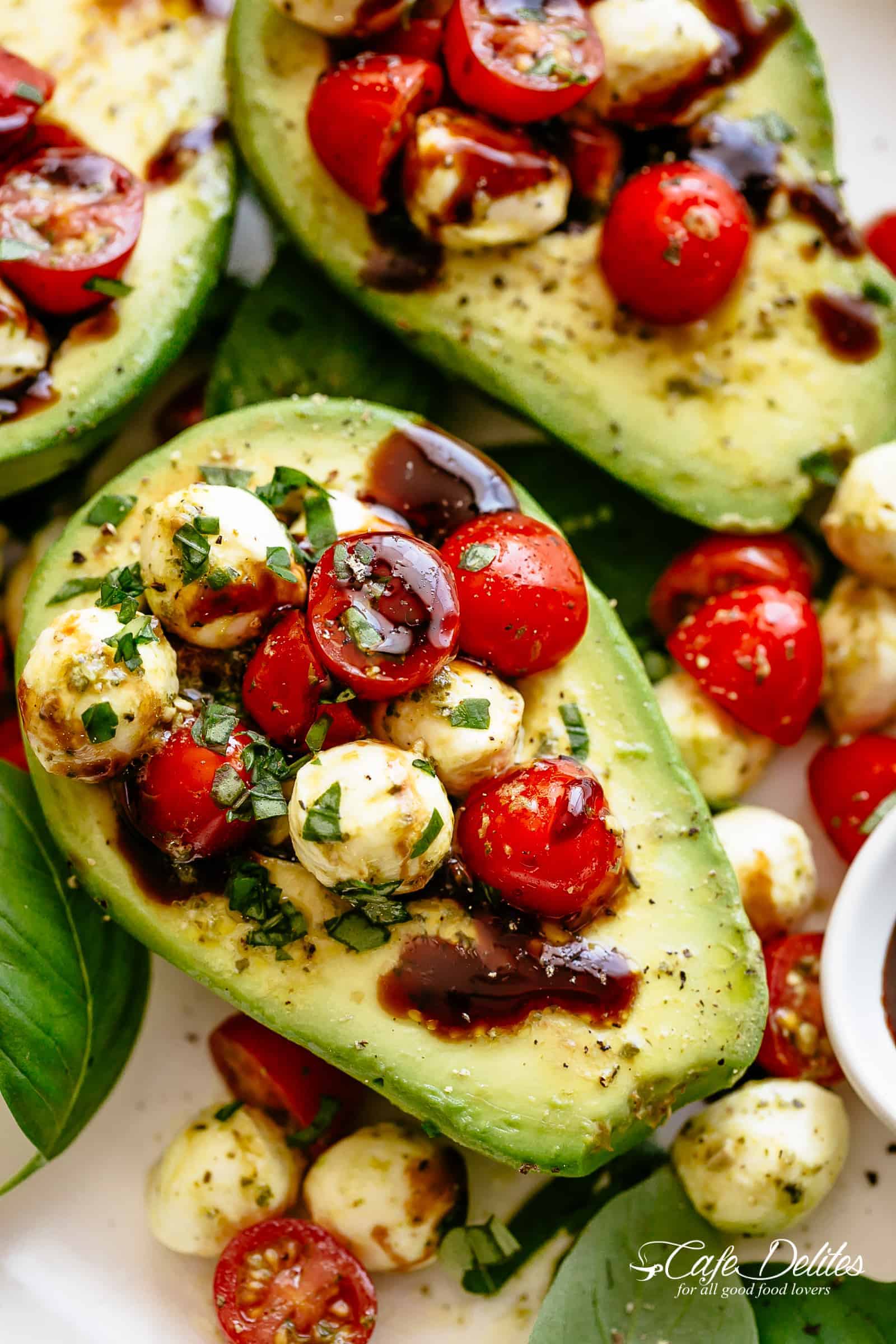 Basil Pesto Caprese Stuffed Avocado drizzled with balsamic glaze make an incredible light lunch or snack! Take creamy avocados to a different level! Sweet and juicy grape/cherry tomatoes with fresh mozzarella balls are tossed through basil pesto and spooned into avocado halves! | cafedelites.com