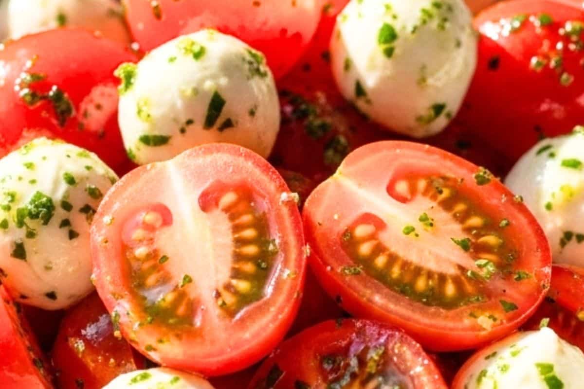 Add the halved cherry tomatoes and bocconcini to the bowl with the dressings.