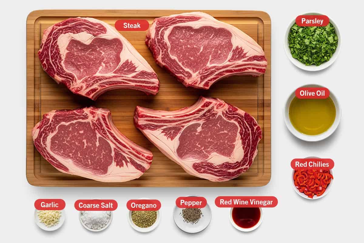 Top shot of ingredients: Steak, parsley, olive oil, red chillies, garlic, coarse salt, oregano, pepper, and red wine vinegar.