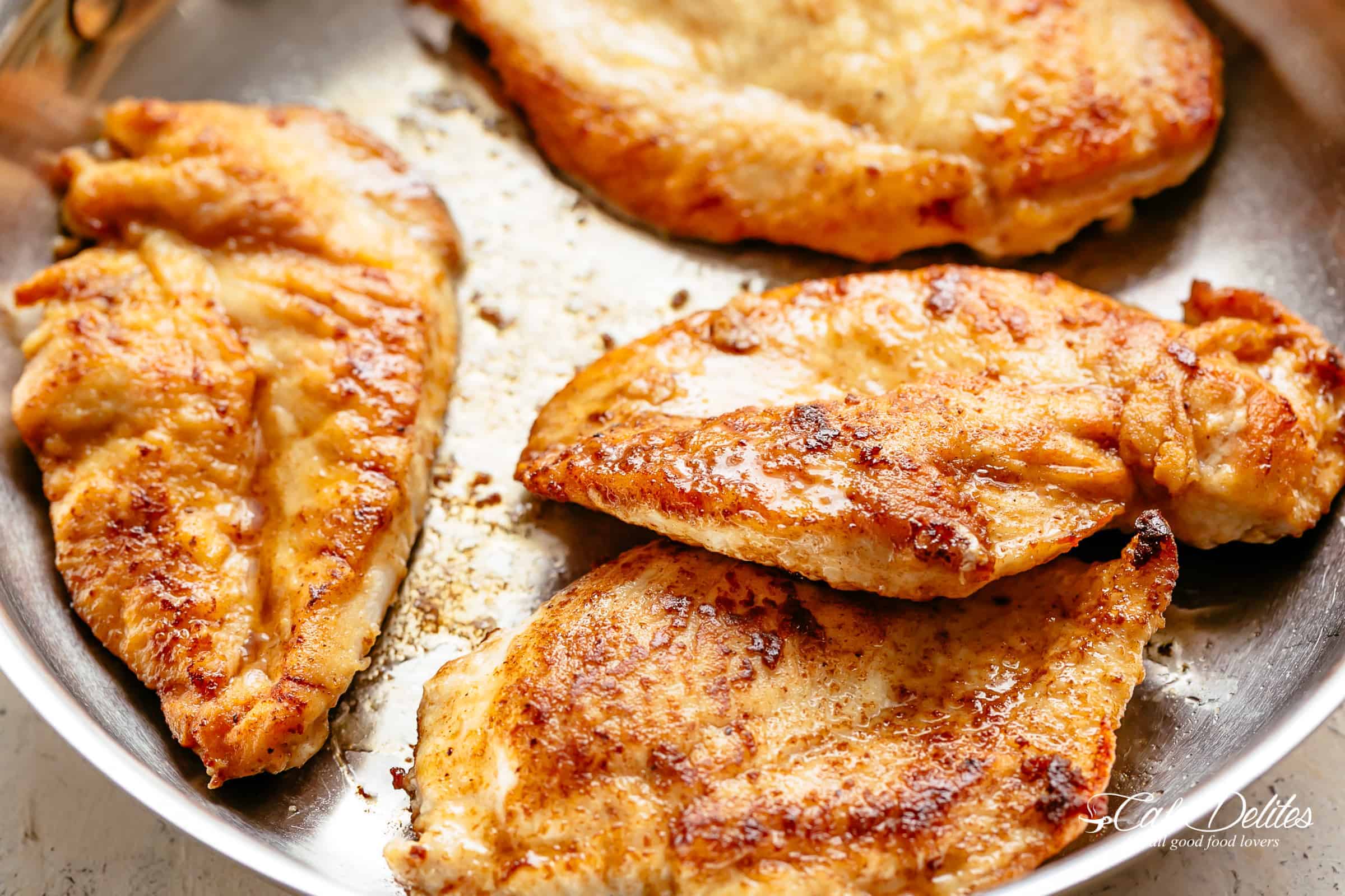 Chicken breasts being fried in a pan. 