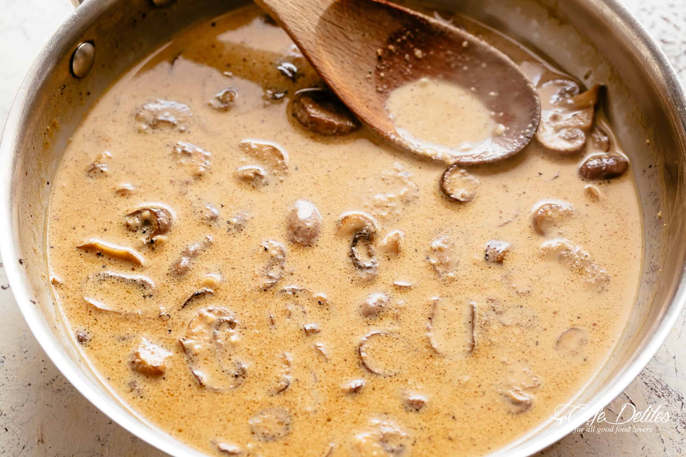 Thick and creamy Marsala sauce with a wooden spoon resting on the side of the pan. 