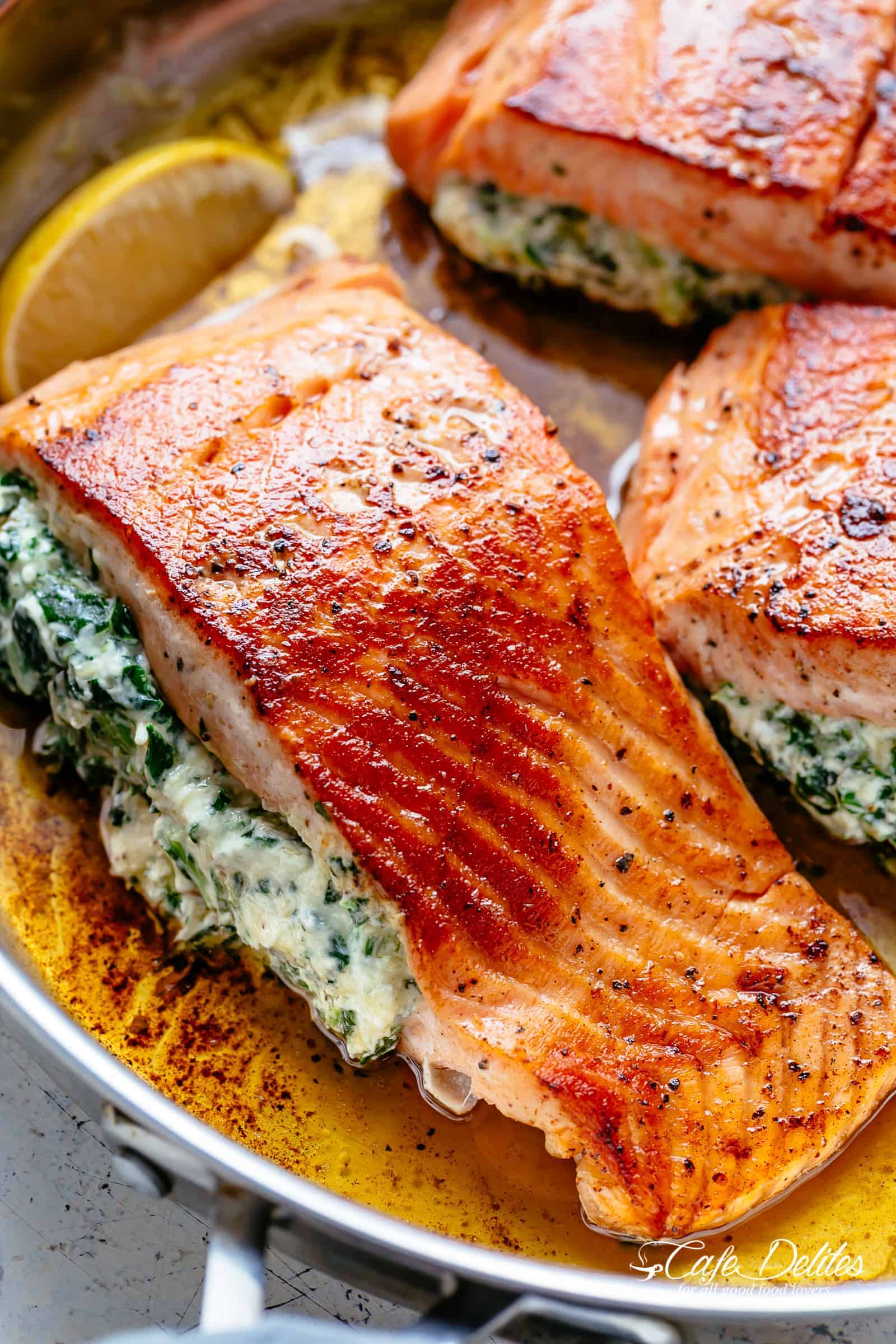 Creamy Spinach Stuffed Salmon in garlic butter är ett nytt läckert sätt att njuta av lax! Fylld med färskost, spenat, parmesanost och vitlök slår den här laxen allt som finns på en restaurang. Ditt nya favoritlaxrecept innehåller pannstekta OCH ugnsbakade metoder! | cafedelites.com