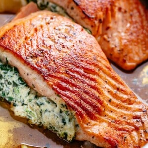 Creamy Spinach Stuffed Salmon in garlic butter is a new delicious way to enjoy salmon! Filled with cream cheese, spinach, parmesan cheese and garlic, this salmon beats than anything found in a restaurant.