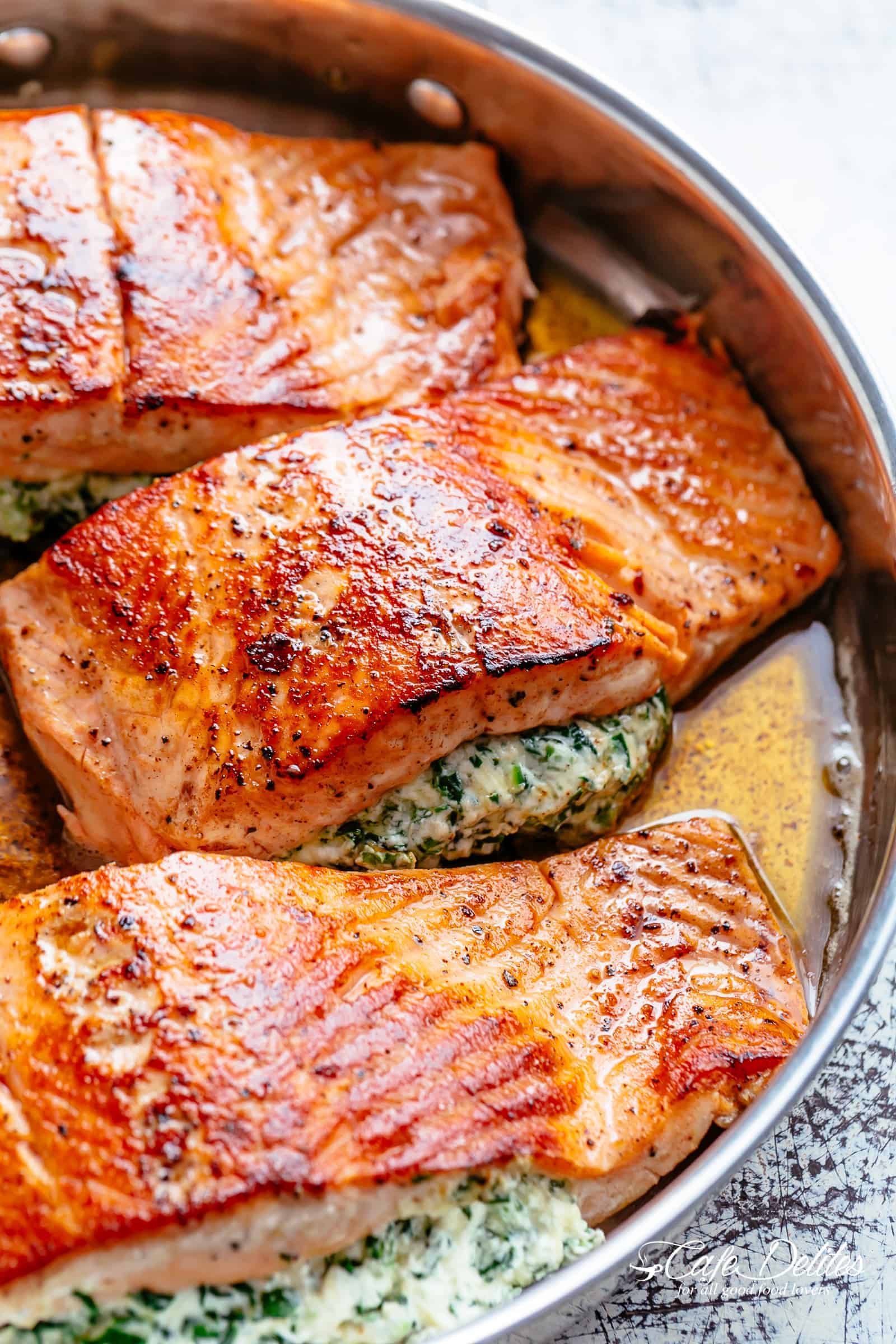 A close up of Creamy Spinach Stuffed Salmon in garlic butter. Filled with cream cheese, spinach, parmesan cheese and garlic. Recipe includes pan fried AND oven baked methods! | cafedelites.com