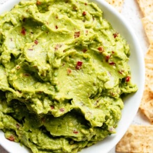 Top view of The best, creamy Guacamole is so easy to make and better than anything found in a jar! Homemade Guacamole takes minutes to make and is so incredibly delicious! Perfect for a party as an appetizer OR just a simple snack! Use as a topping for your favourite fajitas, tacos and even carnitas.