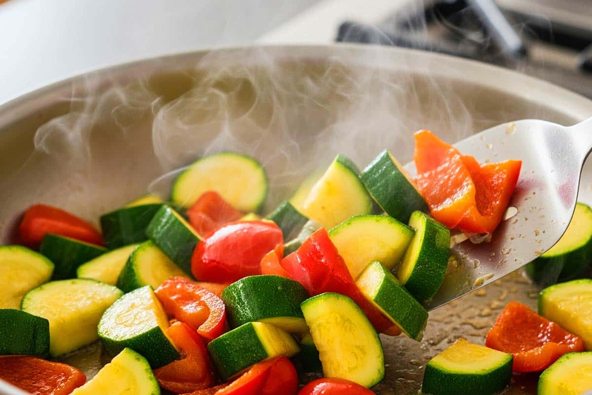 Stir-frying the zucchini and bell pepper.