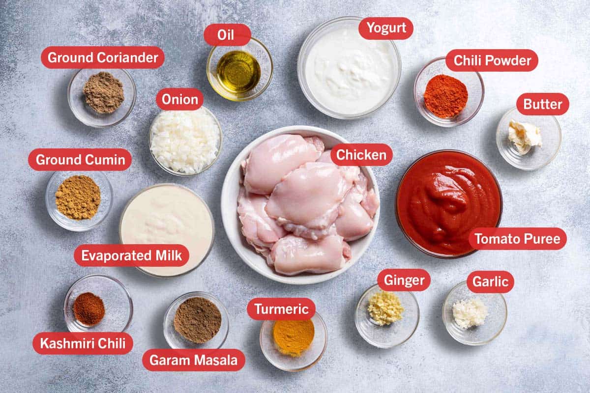 ground coriander, oil, yogurt, chili powder, onion, chicken, butter, ground cumin, evaporated milk, tomato puree, kashmiri chili, garam masala, tumeric, ginger and garlic all laid out in bowls and labelled