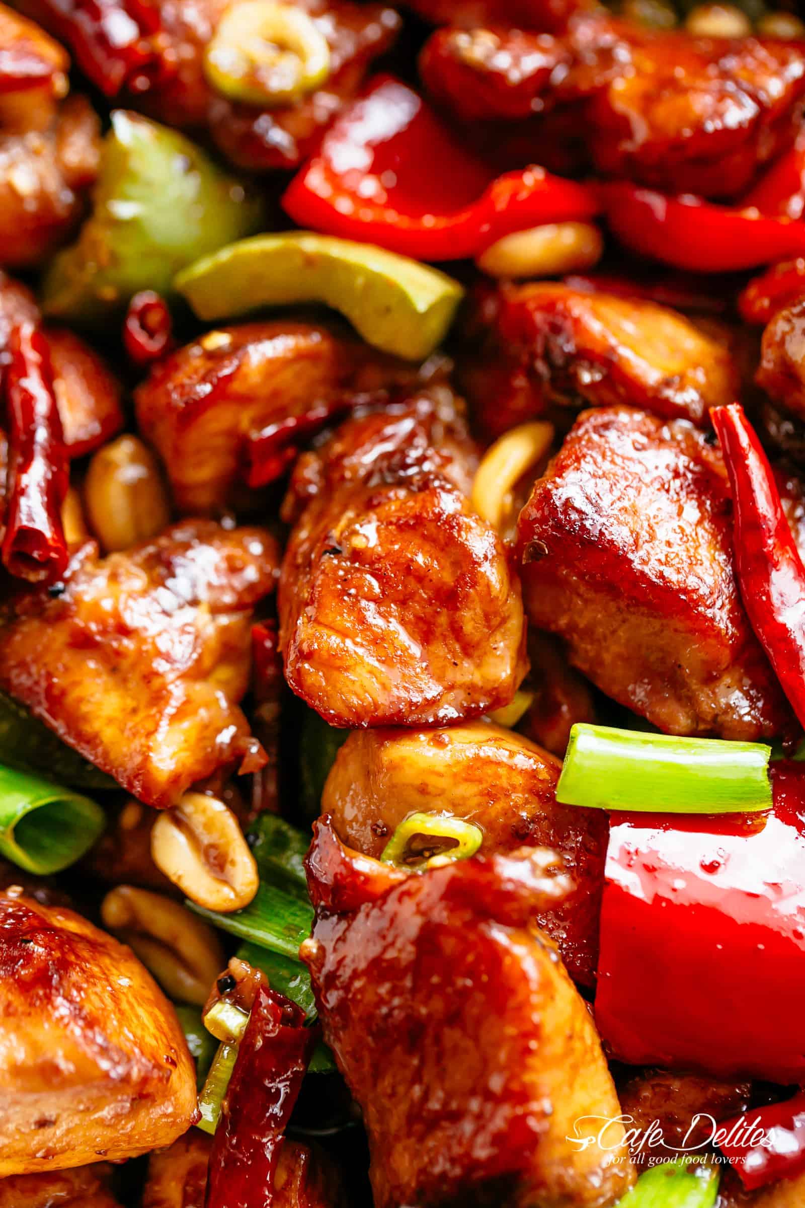 Close up of Kung Pao Chicken in a sticky Kung Pao sauce with green and red chopped vegetables picked in with chicken pieces. 