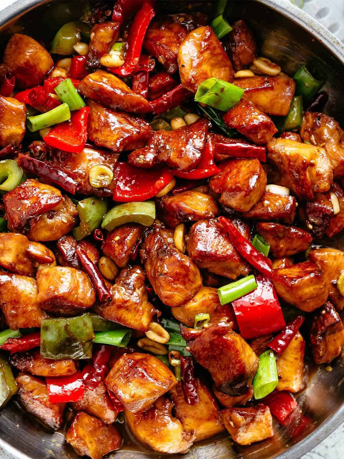 Kung Pao Chicken | cafedelites.com Close up image of Kung Pao Chicken in a sticky Kung Pao sauce with green and red chopped vegetables picked in with chicken pieces.
