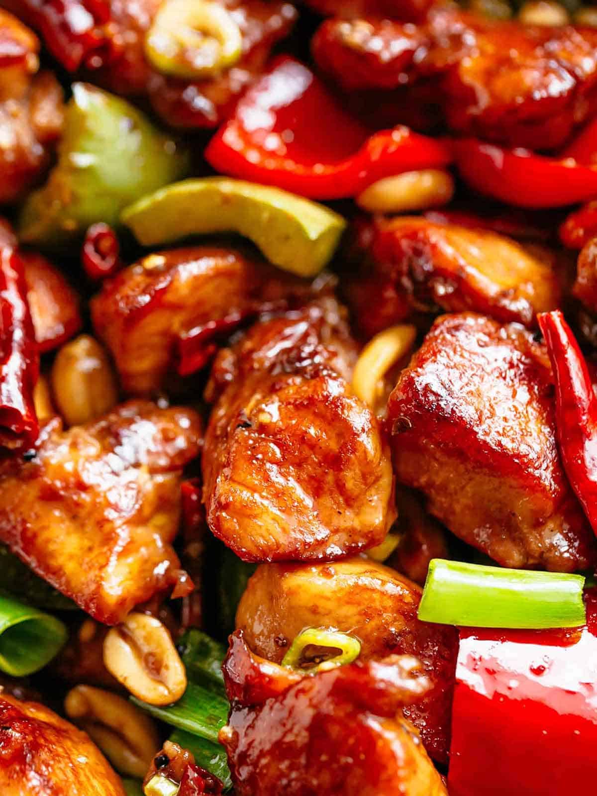 Close up image of Kung Pao Chicken in a sticky Kung Pao sauce with green and red chopped vegetables picked in with chicken pieces. 