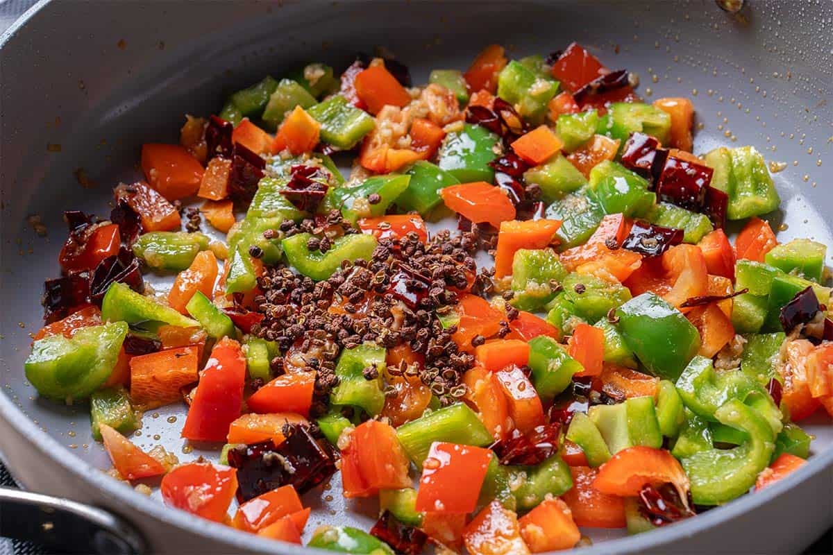 garlic, ginger, chili diced peppers (capsicums) and Sichuan peppercorns in a wok cooking